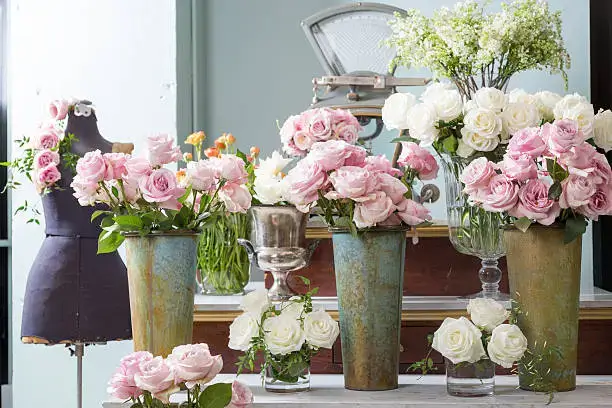 Elegant flower arrangements with pink and white roses in vintage vases at a stylish flower shop in Dubai.