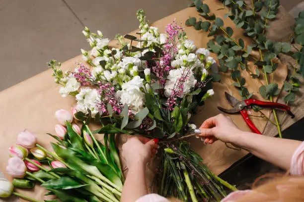 Florist arranging a fresh flower bouquet with pink and white blooms at a flower shop in Dubai