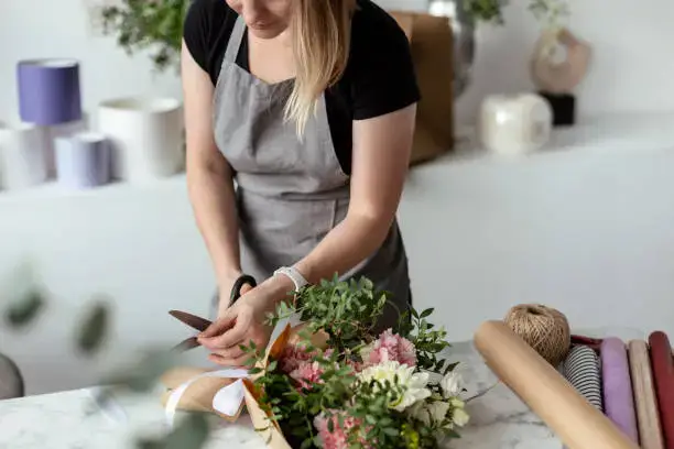 Beautiful woman arranging a vibrant flower bouquet in a flower shop in the UAE.