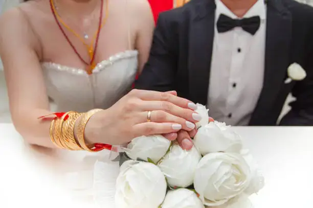 Bride and groom holding hands over a bouquet of white roses, symbolizing love and unity—ideal floral arrangement for weddings in the UAE. White rose near me UAE.