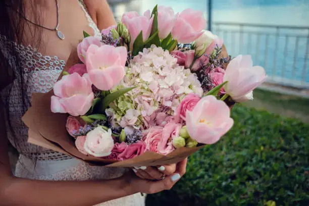 Elegant pink tulip and rose bouquet held by woman near waterfront – flower shop Dubai
